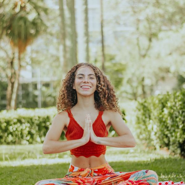 Smiling woman stretching gently on a yoga mat outdoors.